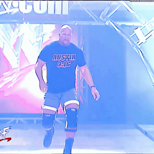 A Man Wearing A Black Shirt That Says Austin 3:16 Walks On A Stage GIF