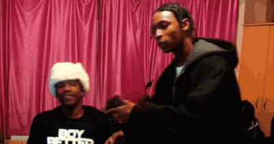 A Man Wearing A Black Shirt That Says Boy Better Is Standing Next To Another Man GIF