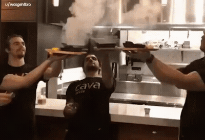 A Man Wearing A Black Shirt That Says Cava On It Holds Up A Tray Of Food GIF