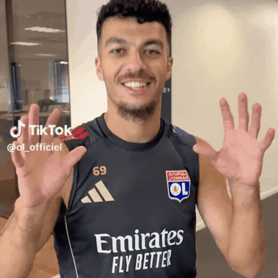 A Man Wearing A Black Shirt That Says Emirates Fly Better On It GIF