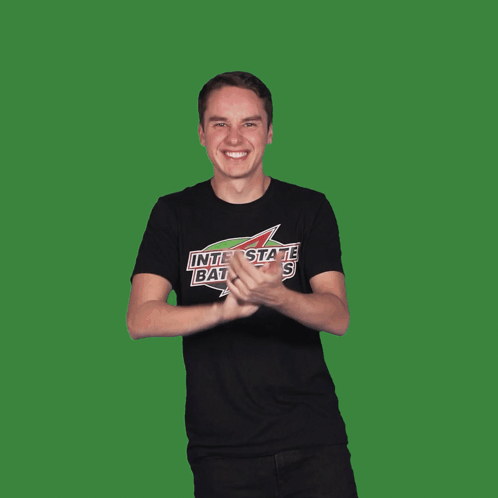 A Man Wearing A Black Shirt That Says Interstate Batteries Is Flexing His Muscles GIF