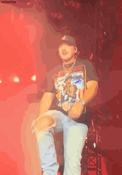 A Man Wearing A Black Shirt That Says Iron Maiden Is Dancing On A Stage GIF