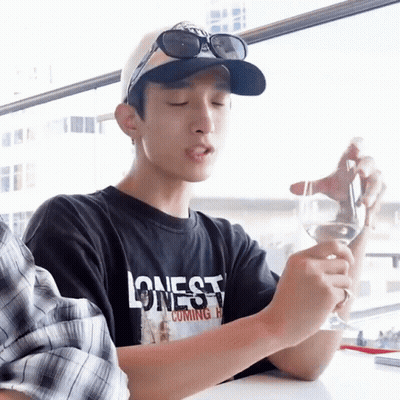 A Man Wearing A Black Shirt That Says Lonesome Coming Home Holds A Wine Glass GIF