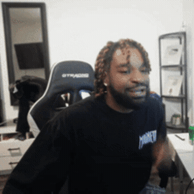 A Man Wearing A Black Shirt That Says Monkey Is Sitting In A Gaming Chair GIF
