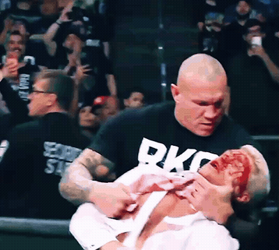 A Man Wearing A Black Shirt That Says Rkc On It Is Holding Another Man GIF