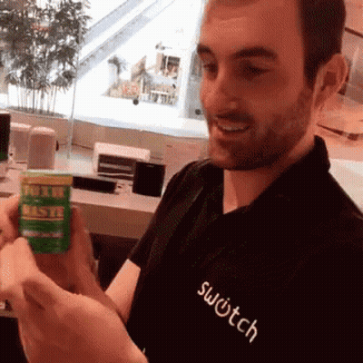 A Man Wearing A Black Shirt That Says Switch Holds A Green Bottle GIF