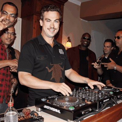 A Man Wearing A Black Shirt With A Cockroach On It Is Playing Music On A Jasthennial Dj Mixer GIF
