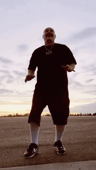 A Man Wearing A Black Shirt With A Pendant That Says ' Reggae ' On It GIF