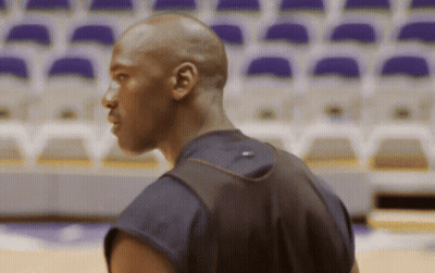 A Man Wearing A Black Shirt With A Red Stripe On The Back Is Standing In Front Of Empty Seats GIF