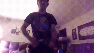 A Man Wearing A Black Shirt With A Vault Boy Design On It GIF