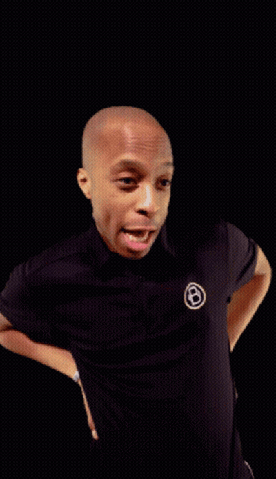 A Man Wearing A Black Shirt With A White Circle With The Letter B On It GIF