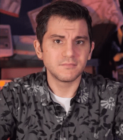A Man Wearing A Black Shirt With A Zelda Logo On It GIF