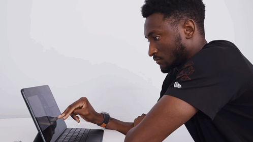 A Man Wearing A Black Shirt With The Letter E On It Is Using A Laptop GIF
