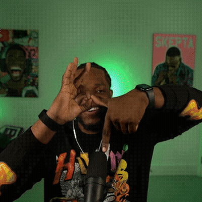 A Man Wearing A Black Shirt With The Letter H On It Stands In Front Of A Microphone GIF