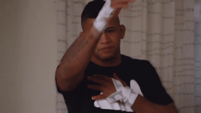 A Man Wearing A Black Shirt With The Letter T On The Front GIF