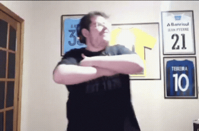 A Man Wearing A Black Shirt With The Number 10 On It Is Standing In Front Of A Wall With Jerseys On It . GIF