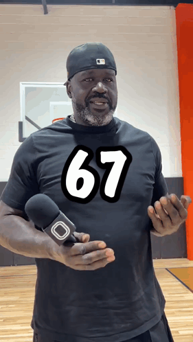 A Man Wearing A Black Shirt With The Number 67 On It Holds A Microphone GIF