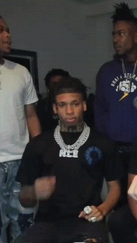 A Man Wearing A Black Shirt With The Word Nice On It Stands In A Crowd GIF