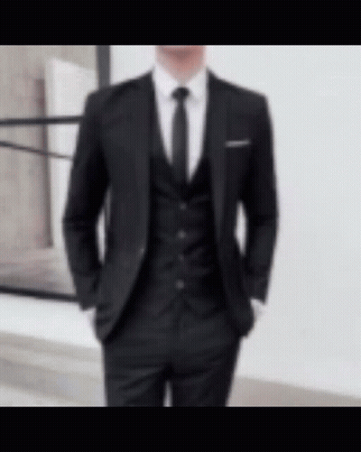 A Man Wearing A Black Suit And Tie Is Standing In Front Of A Window . GIF