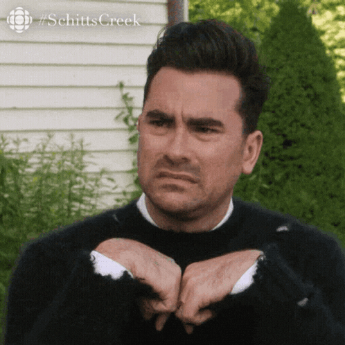 A Man Wearing A Black Sweater Is Making A Funny Face . GIF