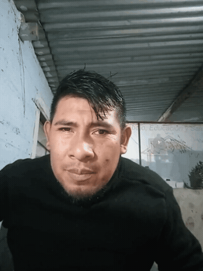 A Man Wearing A Black Sweater Stands In Front Of A Sign That Says Educacion Y Salud GIF