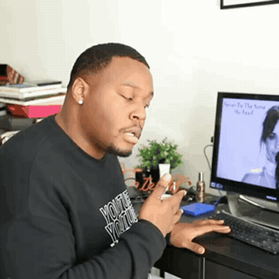 A Man Wearing A Black Sweatshirt That Says " You 'Re Youth " Is Sitting In Front Of A Computer GIF