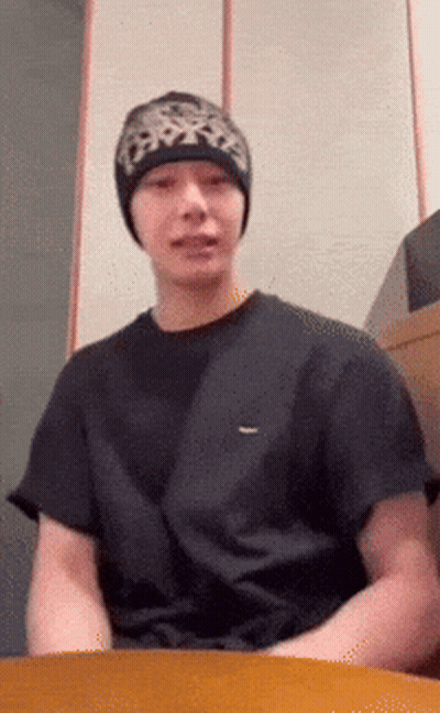 A Man Wearing A Black T-Shirt And A Beanie Looks At The Camera GIF