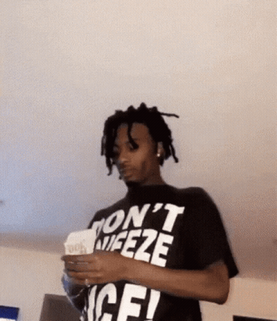 A Man Wearing A Black T-Shirt That Says `` Don 'T Freeze '' Is Holding A Stack Of Money . GIF