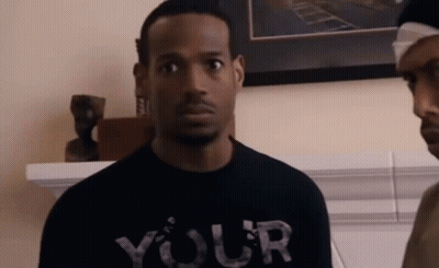 A Man Wearing A Black T-Shirt That Says Your Is Standing Next To Another Man . GIF