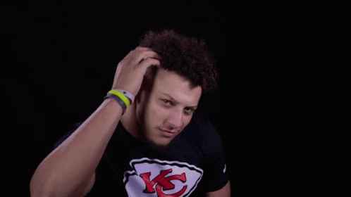 A Man Wearing A Black T-Shirt With A Chiefs Logo On It Is Holding His Hair . GIF