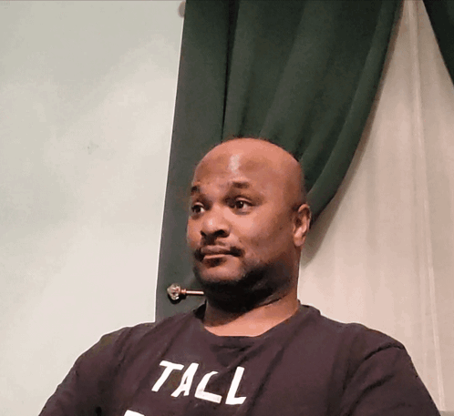 A Man Wearing A Black T-Shirt With The Word Tall On It GIF