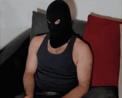 A Man Wearing A Black Tank Top And A Ski Mask Sits On A Couch GIF