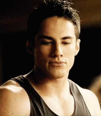 A Man Wearing A Black Tank Top Looks Down At Something GIF