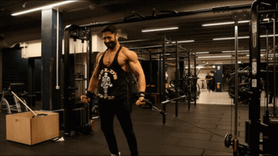 A Man Wearing A Black Tank Top That Says Gold 'S Gym GIF