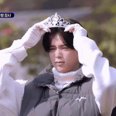 A Man Wearing A Black Vest And White Gloves Is Putting On A Tiara GIF