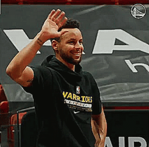 A Man Wearing A Black Warriors T-Shirt Is Waving His Hand . GIF