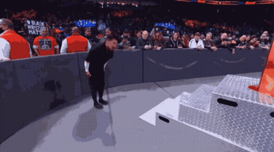 A Man Wearing A Black Wrestler 'S Hat Stands On A Stage GIF