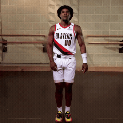 A Man Wearing A Blazers Jersey And Shorts Jumps In The Air GIF
