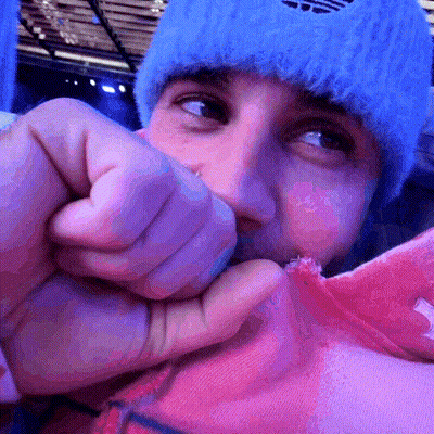 A Man Wearing A Blue Adidas Hat Is Holding A Pink Shirt In His Hand GIF