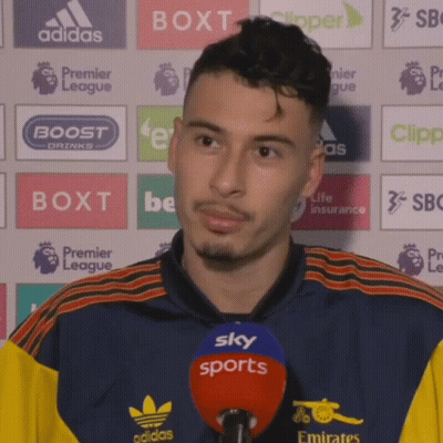 A Man Wearing A Blue And Yellow Adidas Shirt Is Talking Into A Microphone GIF