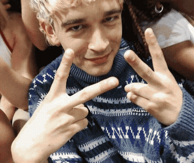 A Man Wearing A Blue Balenciaga Sweater Is Giving The Peace Sign GIF