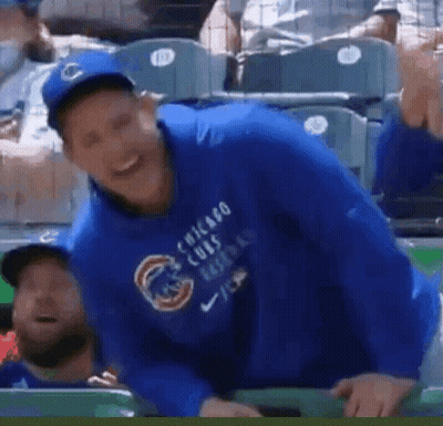 A Man Wearing A Blue Chicago Cubs Sweatshirt Is Sitting In The Dugout . GIF