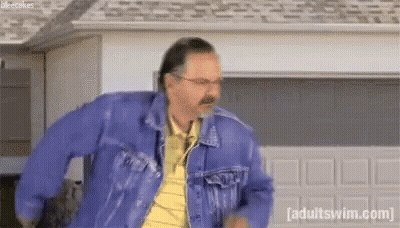 A Man Wearing A Blue Denim Jacket And A Yellow Shirt Is Dancing In Front Of A Garage Door . GIF