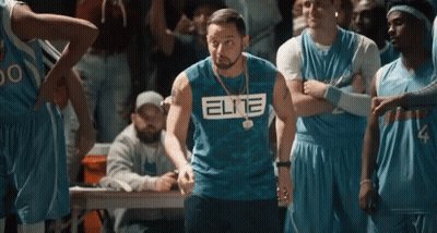 A Man Wearing A Blue Elite Shirt Is Standing In Front Of A Basketball Team . GIF