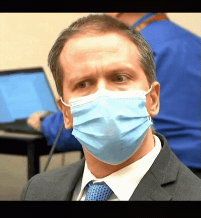 A Man Wearing A Blue Face Mask Looks At The Camera GIF