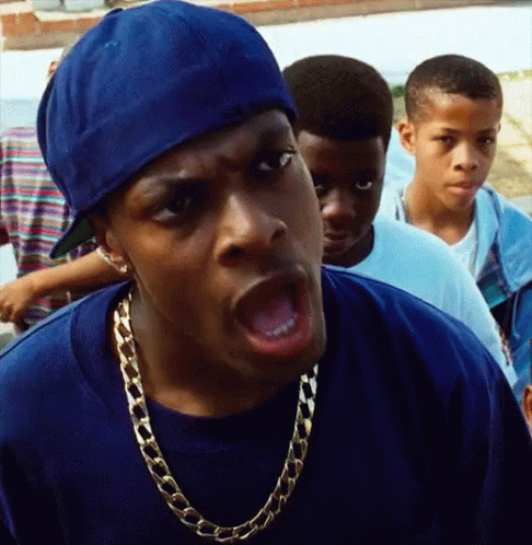 A Man Wearing A Blue Hat And A Gold Chain Looks Angry GIF