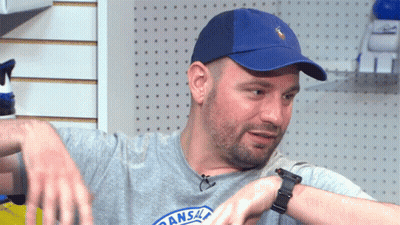 A Man Wearing A Blue Hat And A Kansas City Shirt Looks At His Watch GIF