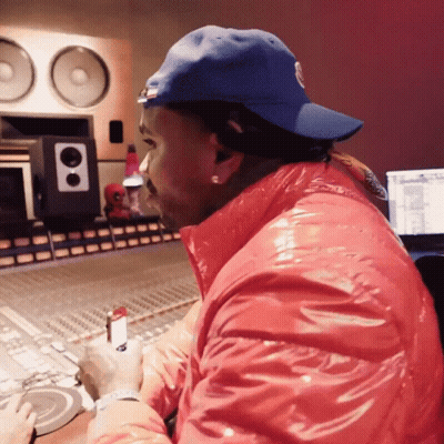A Man Wearing A Blue Hat And A Red Jacket Sits In Front Of A Mixer GIF
