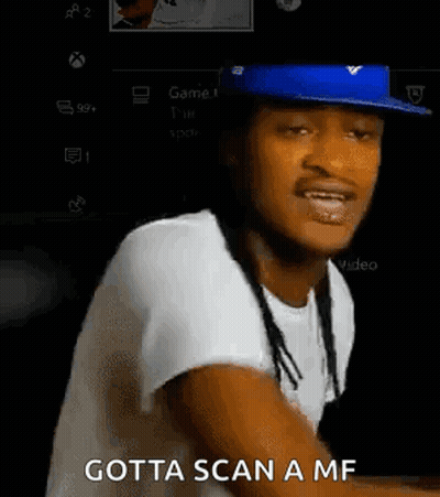 A Man Wearing A Blue Hat And A White Shirt Is Sitting In Front Of A Video Game Controller And Talking . GIF