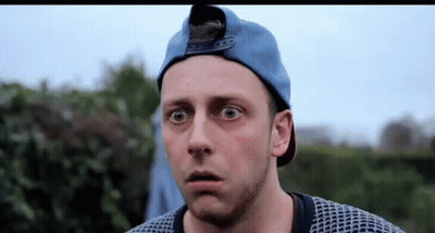 A Man Wearing A Blue Hat And Sweater Is Making A Surprised Face . GIF